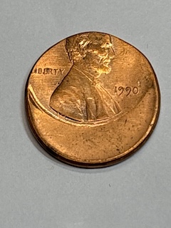 1990 Lincoln penny off-center strike error showing design shifted significantly to one side with blank unstruck area visible on the opposite side